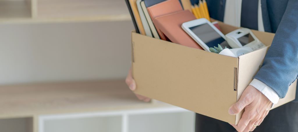 Laid off employee leaving office with items from desk packed into a cardboard box
