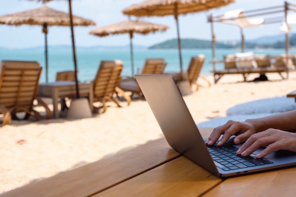 Someone typing on a laptop at the beach